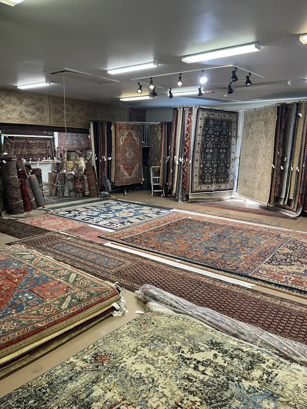 Layered room-size rugs displayed across the gallery floor